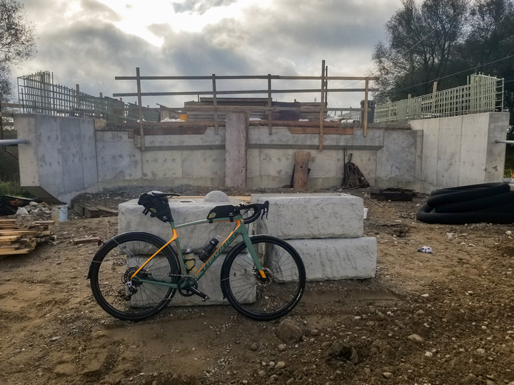 Grimey leaning on a barrier in front of a bridge under a lot of construction