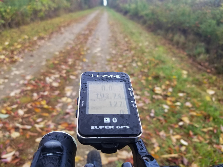 Bike computer speckled with raindrops showing 103.74km, a nice rail-trail in the background