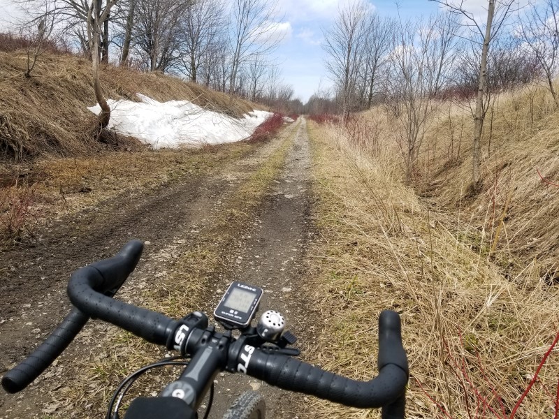 Some snow to the side of a poorly-maintained rail trail